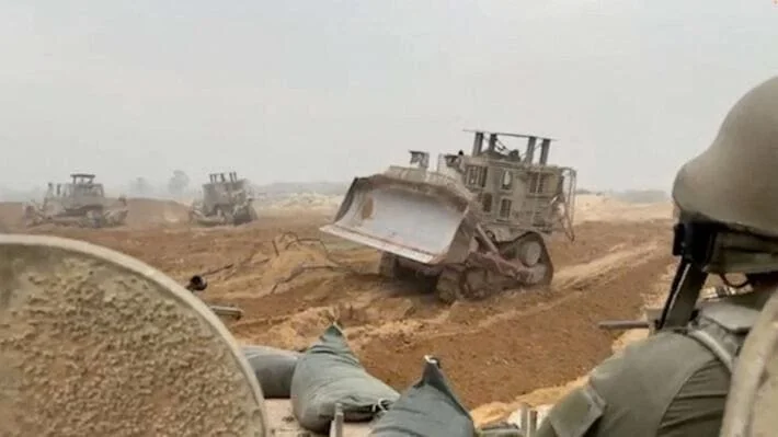 Kendaraan lapis baja Pasukan Pertahanan Israel menunggu saat buldoser lapis baja membersihkan jalur di lokasi yang disebut sebagai Gaza (Foto:AFP)