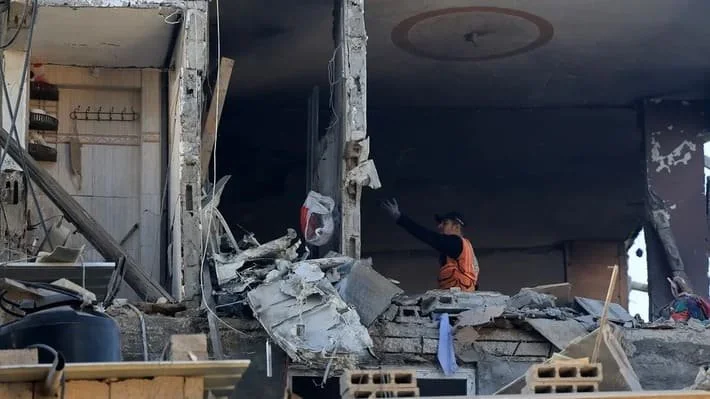 Masyarakat memeriksa kerusakan di sebuah rumah yang terkena bom Israel di Khan Younis di Jalur Gaza selatan pada 3 Desember 2023. (AFP)